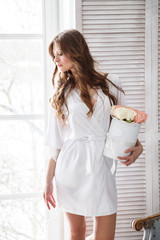 Beautiful sexy girl in a dress and lingerie posing in the morning in the interior, the room, the light room