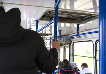 A man holds the handrail on the bus