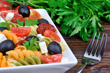 Colorful pasta with vegetable and fork on table