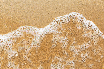 Wave of the sea on yellow sandy beach. Summer vacation background. Wet sand texture.