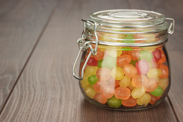 glass jar full of colorful sweets on the wooden table