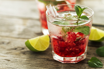 Tasty cold fresh drink lemonade with raspberry, mint, ice and lime in glass. Closeup.
