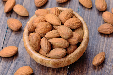Many almonds in a bamboo bowl on table