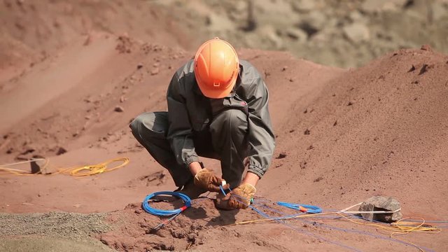 Explosives technicians setting explosives in an open pit iron ore pit for blasting. Extraction of minerals and ore in an open pit.
