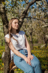 Obraz premium Portrait of beautiful young woman in apple trees blooming park on a sunny day. Smiling girl Happy girl. Happiness concept.