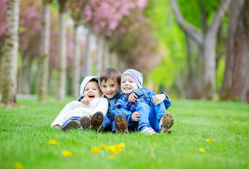 Young boys sitting on grass in park and laughing