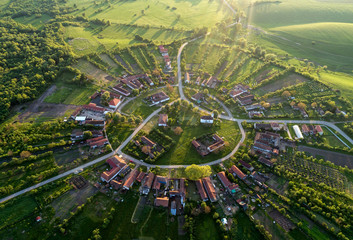 Beautiful unique circular village in Romania seen from above at the sunset by a professional drone with soft nice lens flare  - obrazy, fototapety, plakaty