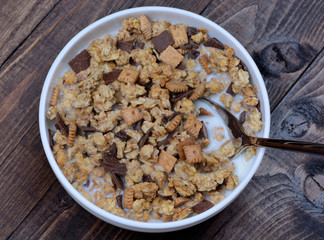 Muesli with milk in a bowl and spoon on table
