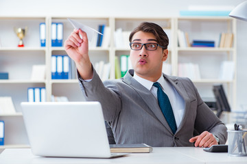 Businessman with paper airplane in office