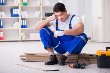 Young worker working on floor laminate tiles