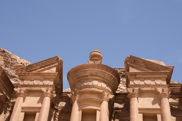 Close up of the carved facade of the Ad-Deir Monastery in Petra Jordan. This ancient building in the Nabatean city has deep blue cloudless sky above. Photographed from below.