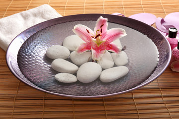 Beautiful spa composition of stones in plate on wooden background