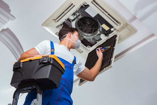 Worker repairing ceiling air conditioning unit