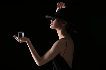 Beautiful young woman with bottle of perfume on dark background
