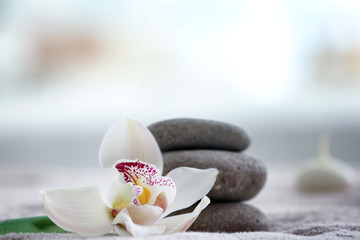 Beautiful spa composition with stones and flower on towel in modern wellness center