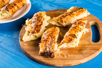 Sliced domestic cheese pie on the round wooden kitchen cutting board