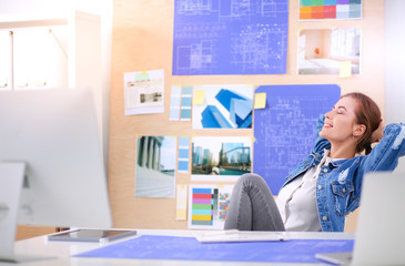 Two young woman standing near desk with instruments, plan and laptop