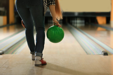 Young woman throwing ball in bowling club