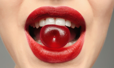 Beautiful young woman with jelly candy in mouth, closeup