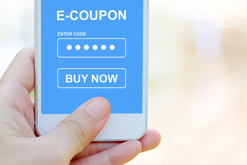 Hand holding smart phone with discount coupon code on screen over blur store background, on line shopping ,business, E-commerce, technology and digital marketing background