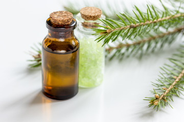 Bottles of essential oil and fir branches for aromatherapy and spa on white table background