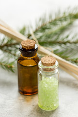 spa with organic spruce oil and sea salt in glass bottles on white table background