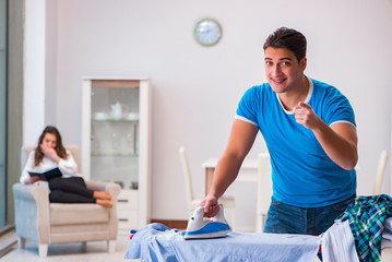 Obraz premium Man husband ironing at home helping his wife
