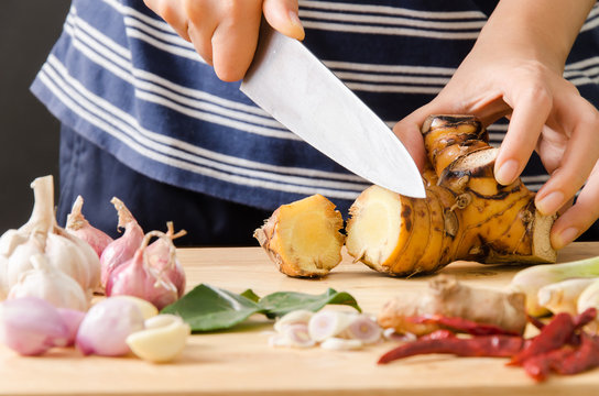 Woman cutting galangal on wooden board prepare for cooking Thai food