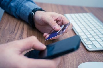Fototapeta premium hands holding credit card and a typing on the phone making online purchase. Copyspace on phone screen