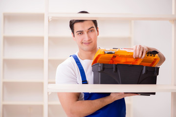 Fototapeta na wymiar Worker man repairing assembling bookshelf