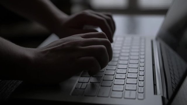 Hands multitasking man working on laptop connecting WiFi internet, businessman hand busy using laptop on desktop, finger on keyboard computer sitting at table, near window