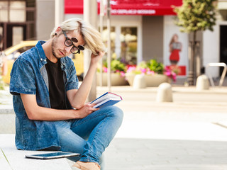 Hipster guy holding notebook sitting on ledge