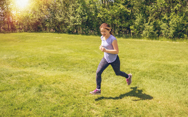 A young girl is running on grass
