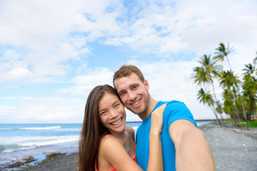 Fototapeta premium Vacation couple walking holding hands on beach travel destination. Happy summer holidays.black sand beach in Big island of Hawaii, USA.
