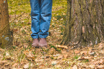 Young kid boy standing lost in forest between two pine tree trunks