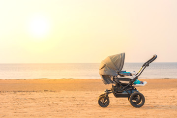 Stroller at sandy beach near sea at sunset