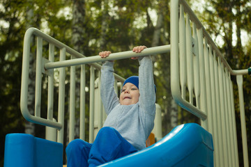 Obraz premium Little child boy sliding down a slide at the summer playground