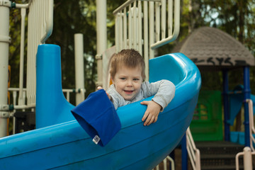 Fototapeta na wymiar Happy kid enjoying active summer vacation. Adorable little child, blond cute toddler boy, having fun outdoors on playground in the park on a sunny day