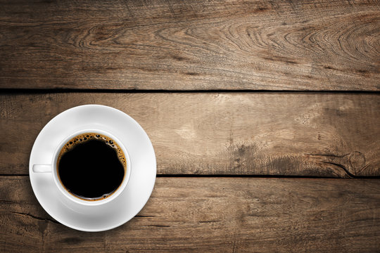 Top view of a white coffee cup on wood background.