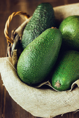 Avocado fruits in basket on wooden rustic background.