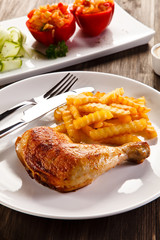 Roast chicken leg with french fries on wooden table
