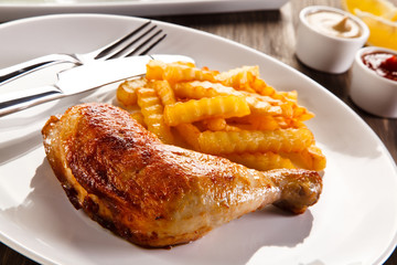 Roast chicken leg with french fries on wooden table
