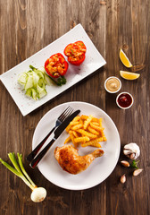 Roast chicken leg with french fries on wooden table