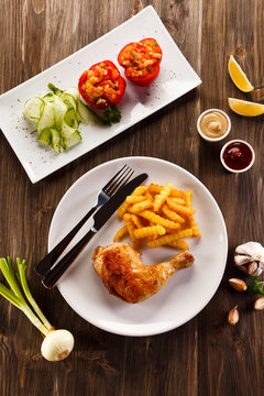 Roast chicken leg with french fries on wooden table