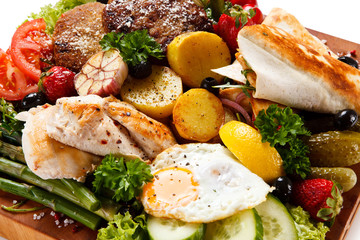 Various meat and vegetables served on cutting board isolated on white