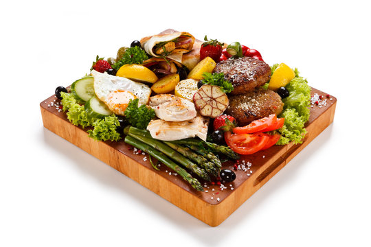 Various meat and vegetables served on cutting board isolated on white
