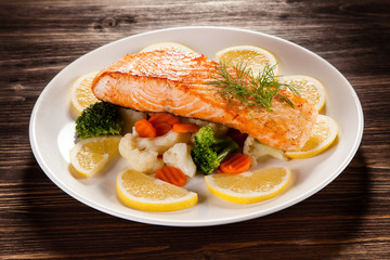 Grilled salmon with boiled vegetables on wooden table