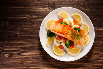 Grilled salmon with boiled vegetables on wooden table