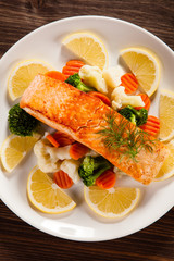 Grilled salmon with boiled vegetables on wooden table