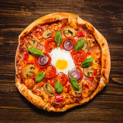 Pizza with egg and mushrooms on wooden table
